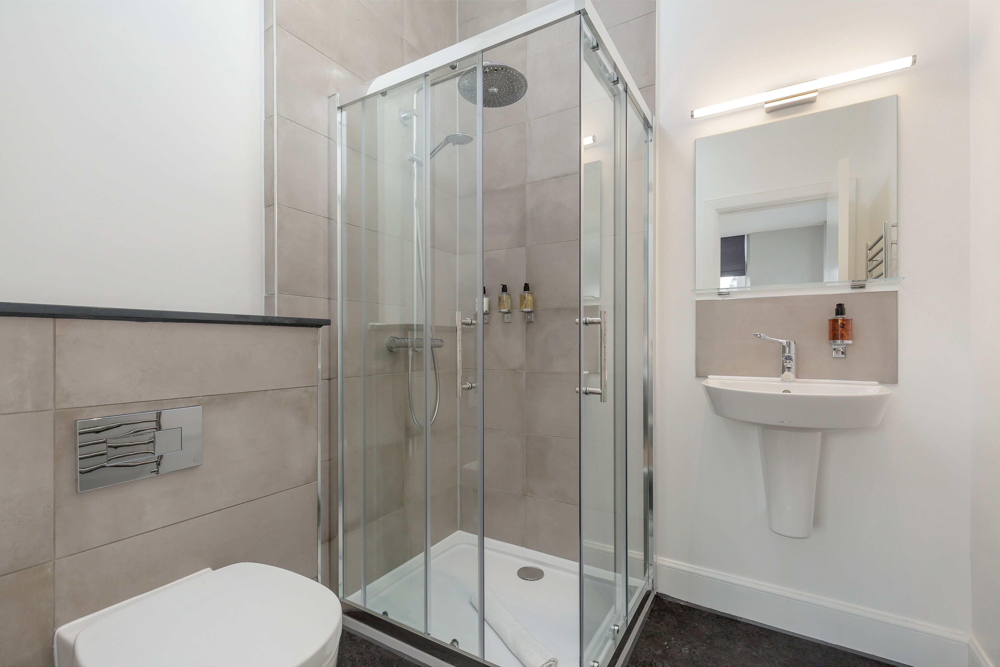 A modern bathroom with a glass-enclosed shower, a white sink, and a toilet.