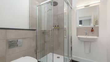 A modern bathroom with a glass-enclosed shower, a white sink, and a toilet.