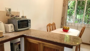 A kitchen with a microwave, toaster, and a bowl of fruit on the counter. - Tropical Garden Self Catering (Mahé Island)