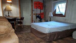 Een kamer met een bed, een bureau met stoel, een lamp en een raam met uitzicht.