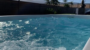 A swimming pool with clear water, surrounded by palm trees and a statue. - Valtisya House Pool & Airport (Telde)