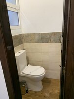Un baño pequeño con inodoro, basurero y zona de ducha.