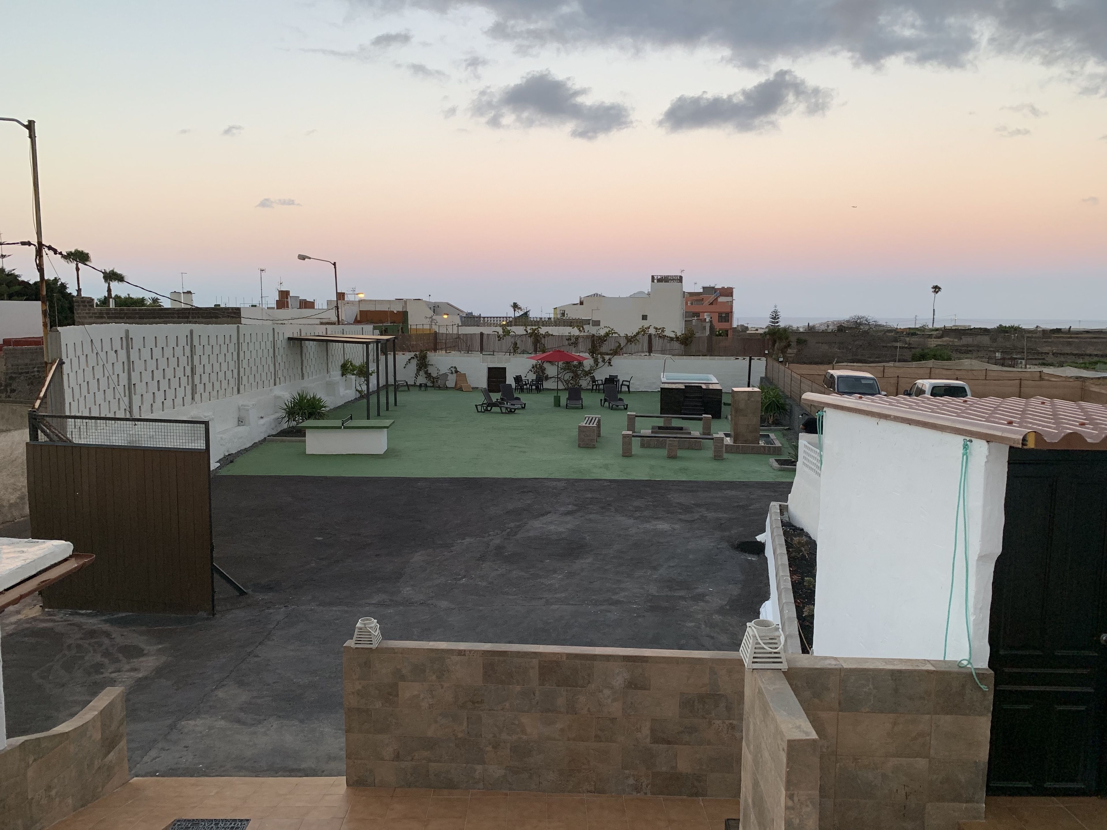Una terraza en la azotea con mobiliario exterior, una piscina pequeña y vistas de la ciudad al atardecer.