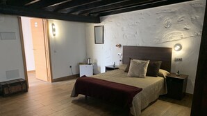 A bedroom with a wooden floor, a bed with a red blanket, a nightstand with a lamp, and a wall-mounted shelf. - Valtisya House Pool & Airport (Telde)