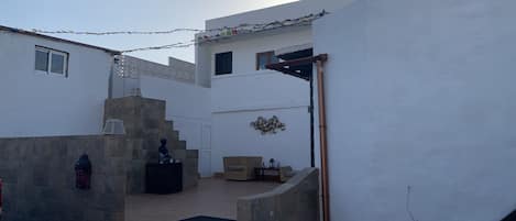 A courtyard with a Buddha statue, a staircase, and a small seating area with cushions.