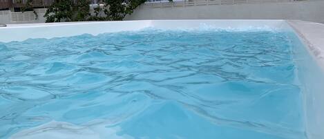 A swimming pool with clear water, surrounded by a wooden fence and trees.