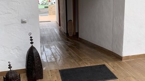 A hallway with a wooden floor, a black mat at the entrance, and a green emergency exit sign. - Valtisya House Pool & Airport (Telde)