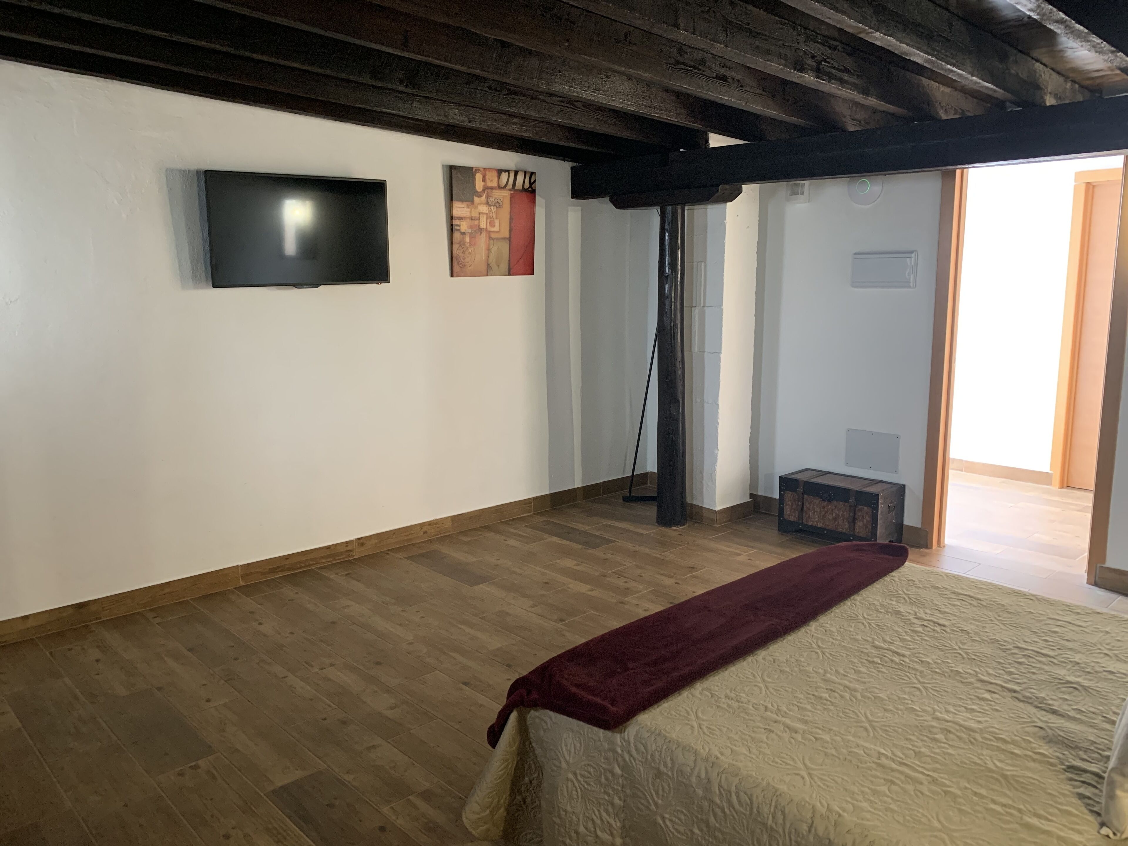 A room with a bed, a television, and artwork on the wall.