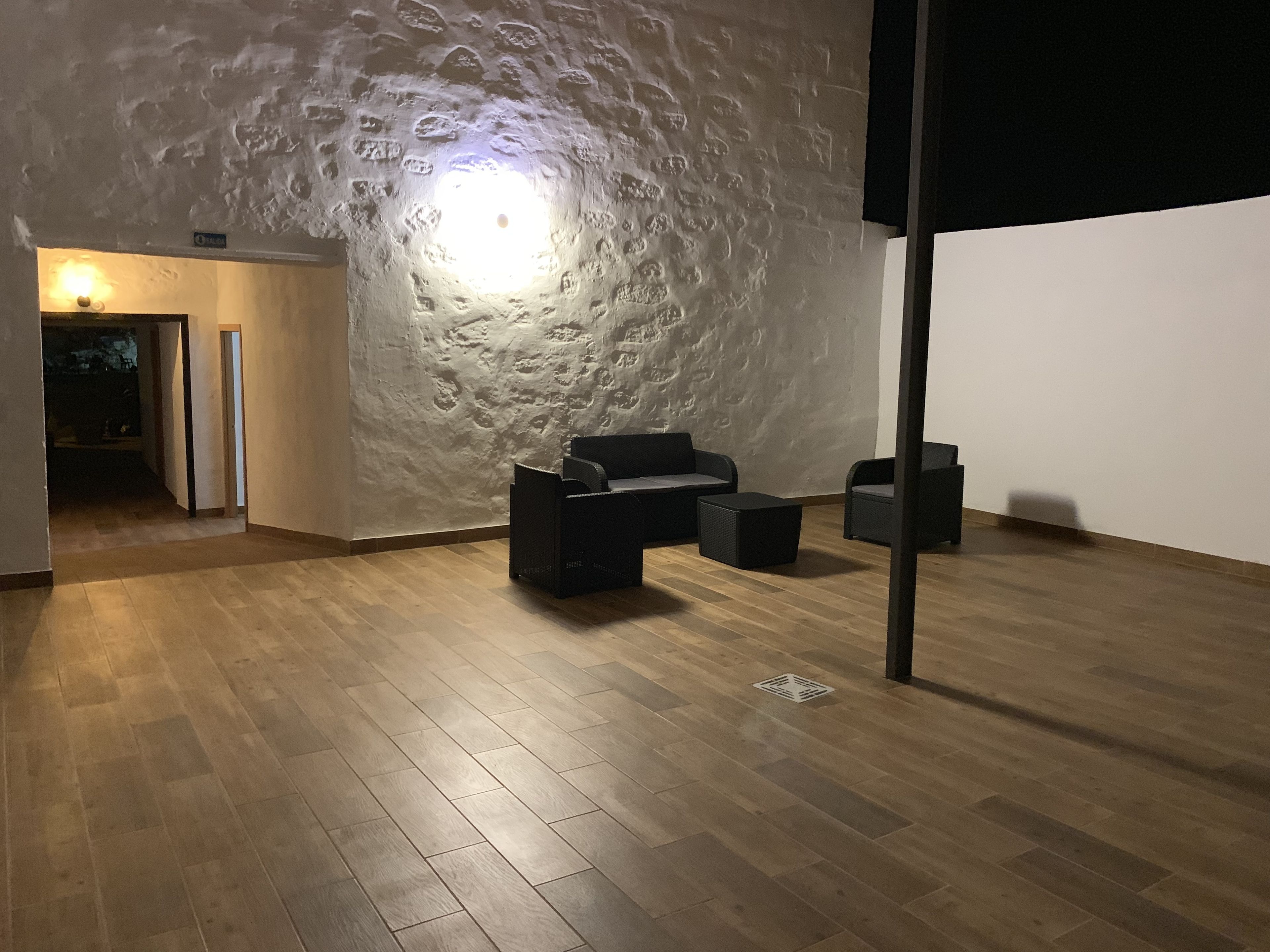 Een kamer met een structuurwand, een houten vloer en twee zwarte banken.
