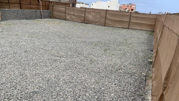 Una terraza con superficie de grava y una valla de madera.