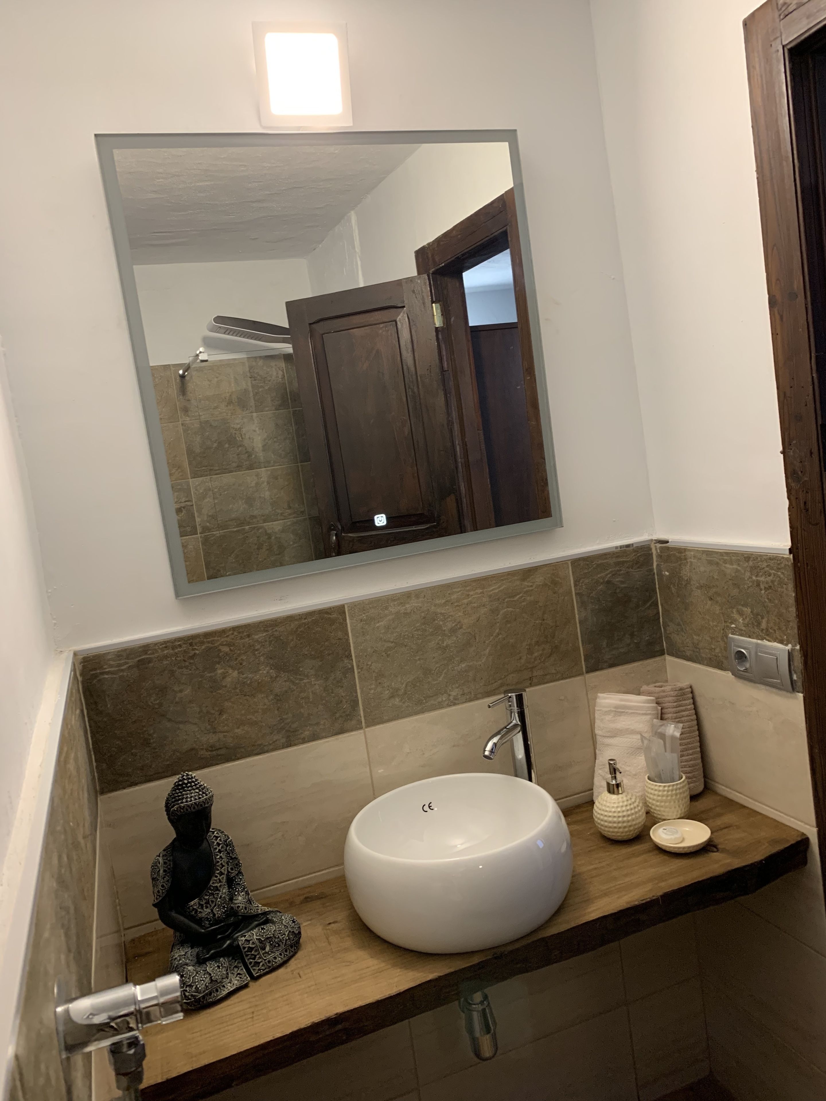 Uma casa de banho com uma pia branca, um espelho e uma bancada de madeira.