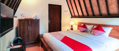 Una habitación de hotel con cama, un banco de madera, un armario y un televisor.