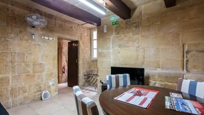 A stone-walled room with a round table, striped chairs, and a fireplace. - Vallettastay Banoffee (Valletta)