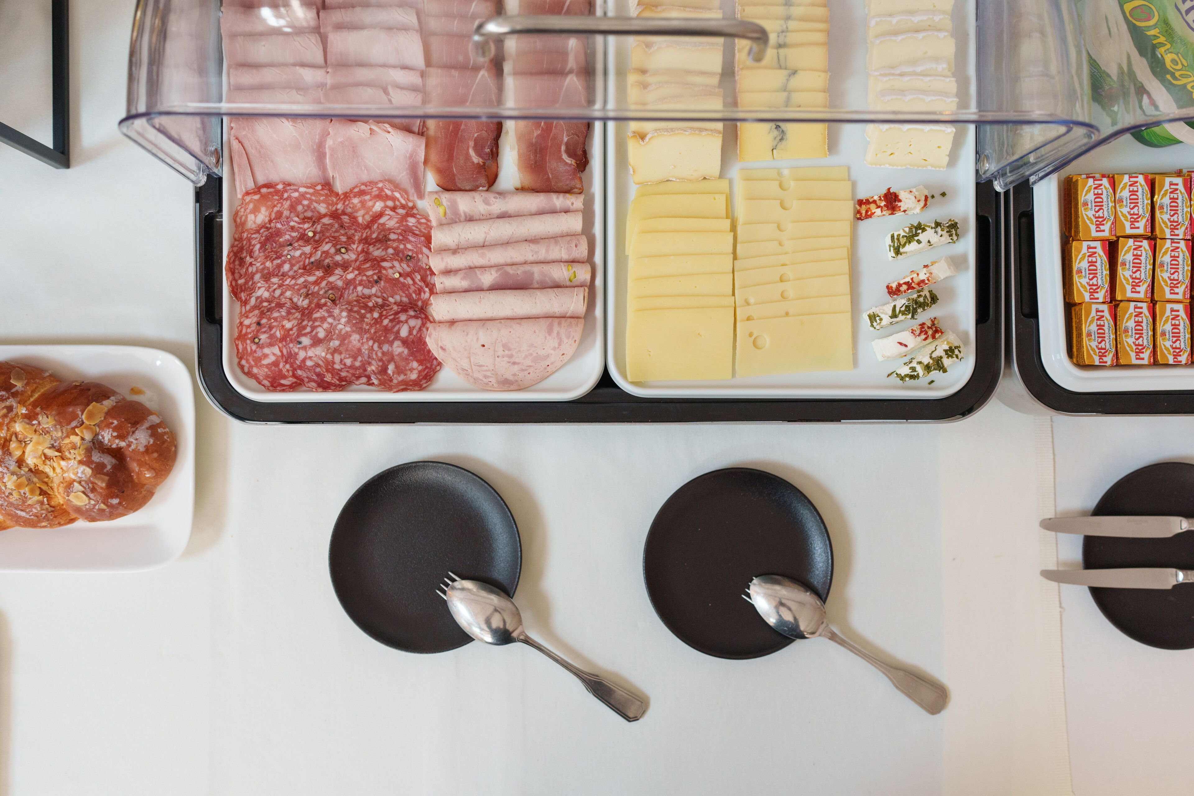 Un bufé con diversos alimentos, incluyendo carnes, quesos y pasteles.
