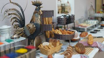 Ein reich gedeckter Buffetstisch mit verschiedenen Brotsorten, Gebäck und einem dekorativen Hahn.