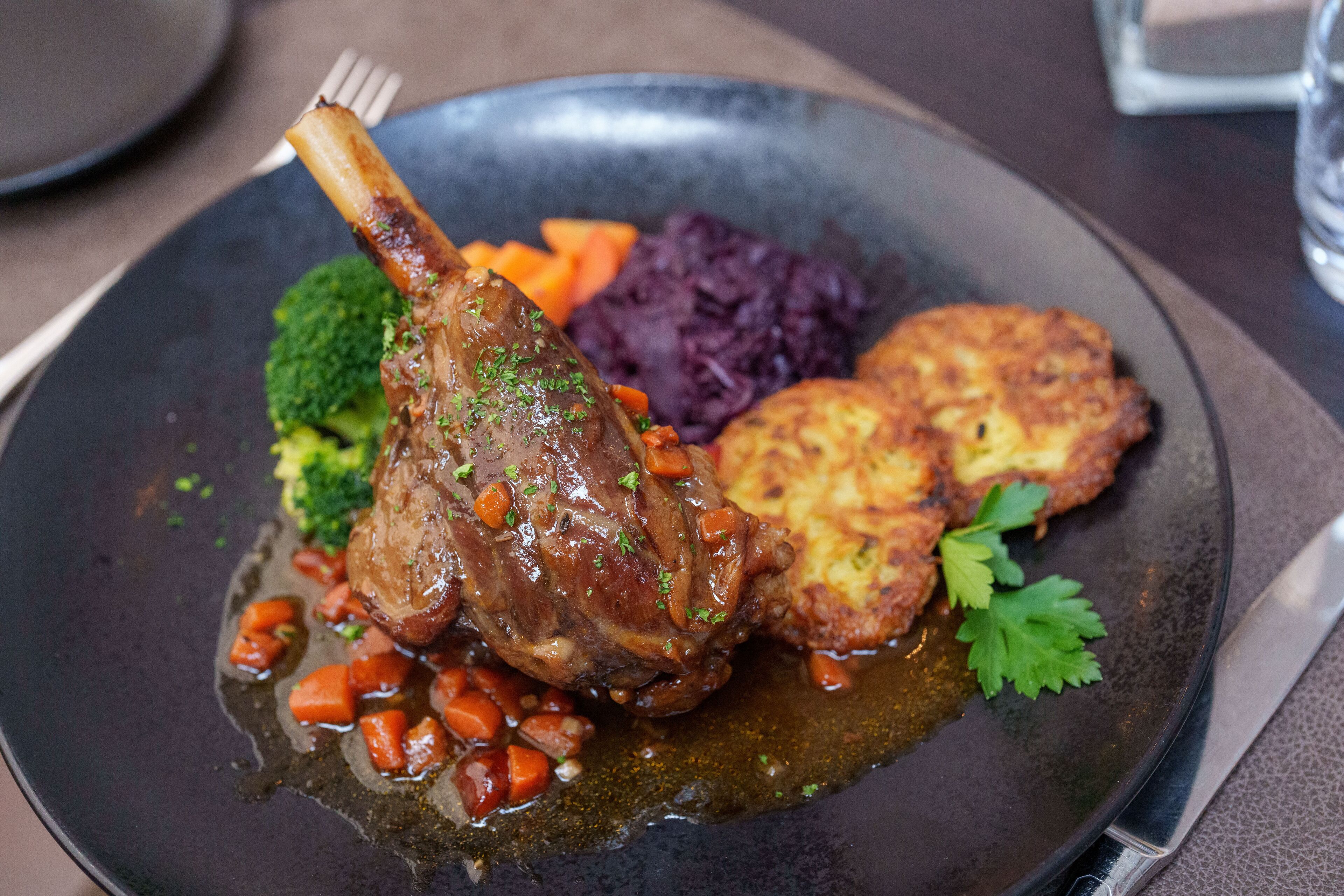 En tallerken med en kalvebryst, gulerødder, broccoli og lilla kål.