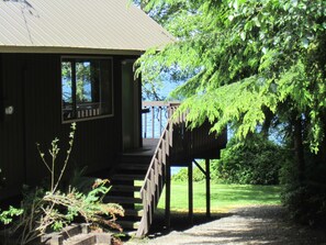 A wooden cabin with a porch and a staircase leading to a deck.