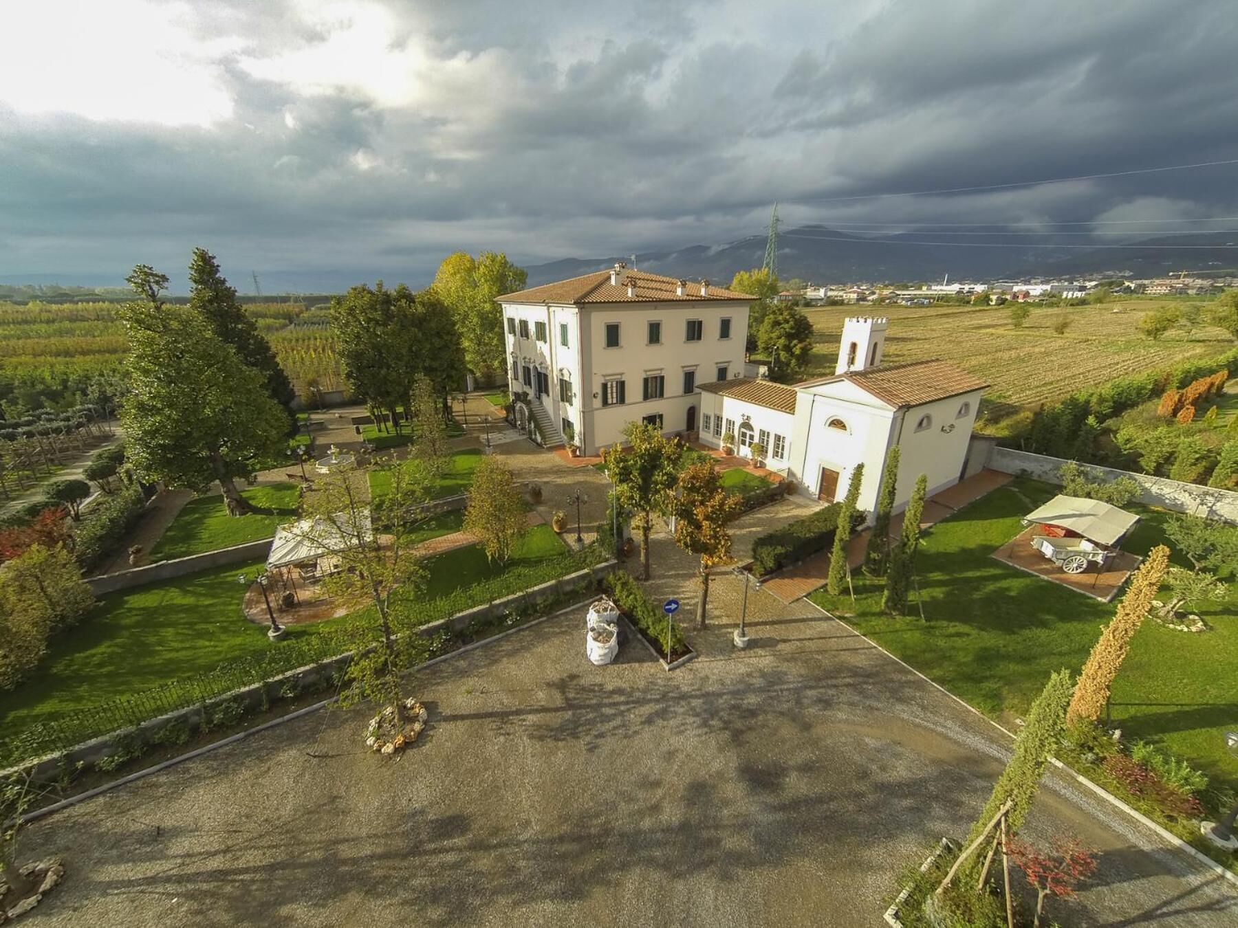 A white building with a central courtyard, surrounded by trees and a view of the countryside.