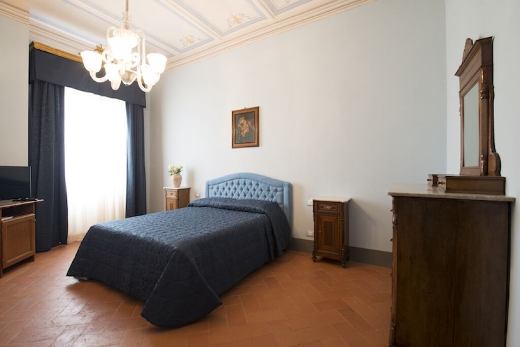 Une chambre à coucher avec un grand lit, un lustre, une commode en bois et un téléviseur.