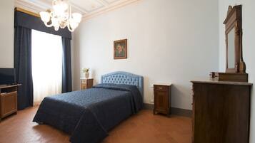 Une chambre à coucher avec un grand lit, un lustre, une commode en bois et un téléviseur.