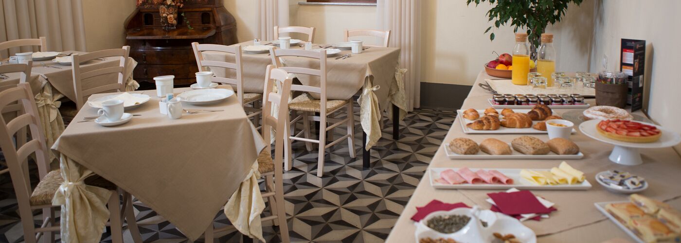 A dining area with multiple tables set for breakfast, including pastries, fruits, and beverages.