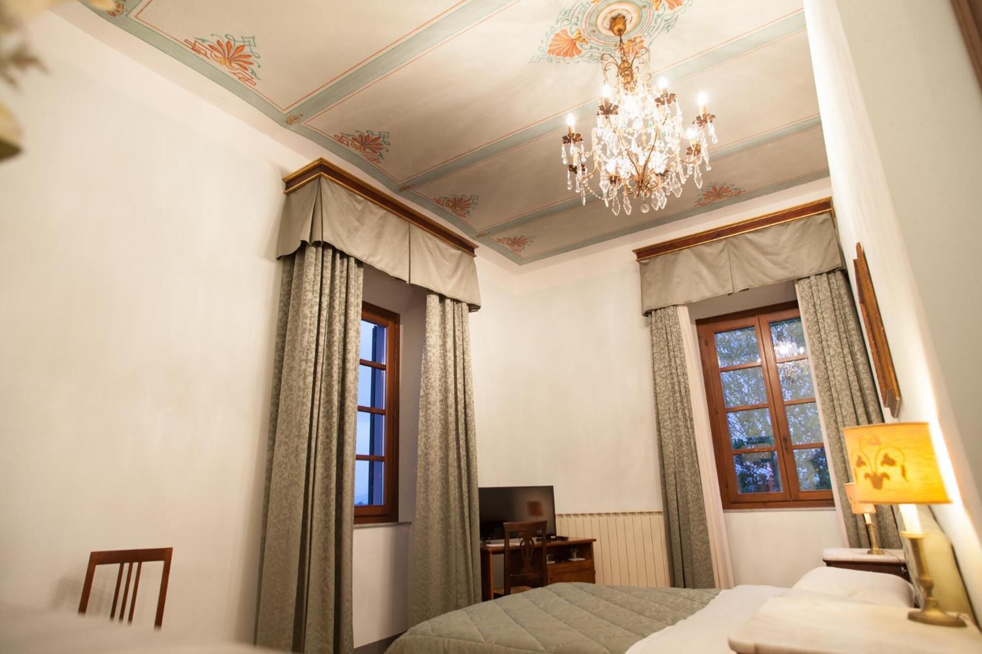 Un dormitorio con cama, escritorio, silla, televisor y candelabro.