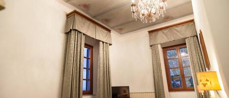 Un dormitorio con cama, escritorio, silla, televisor y candelabro.