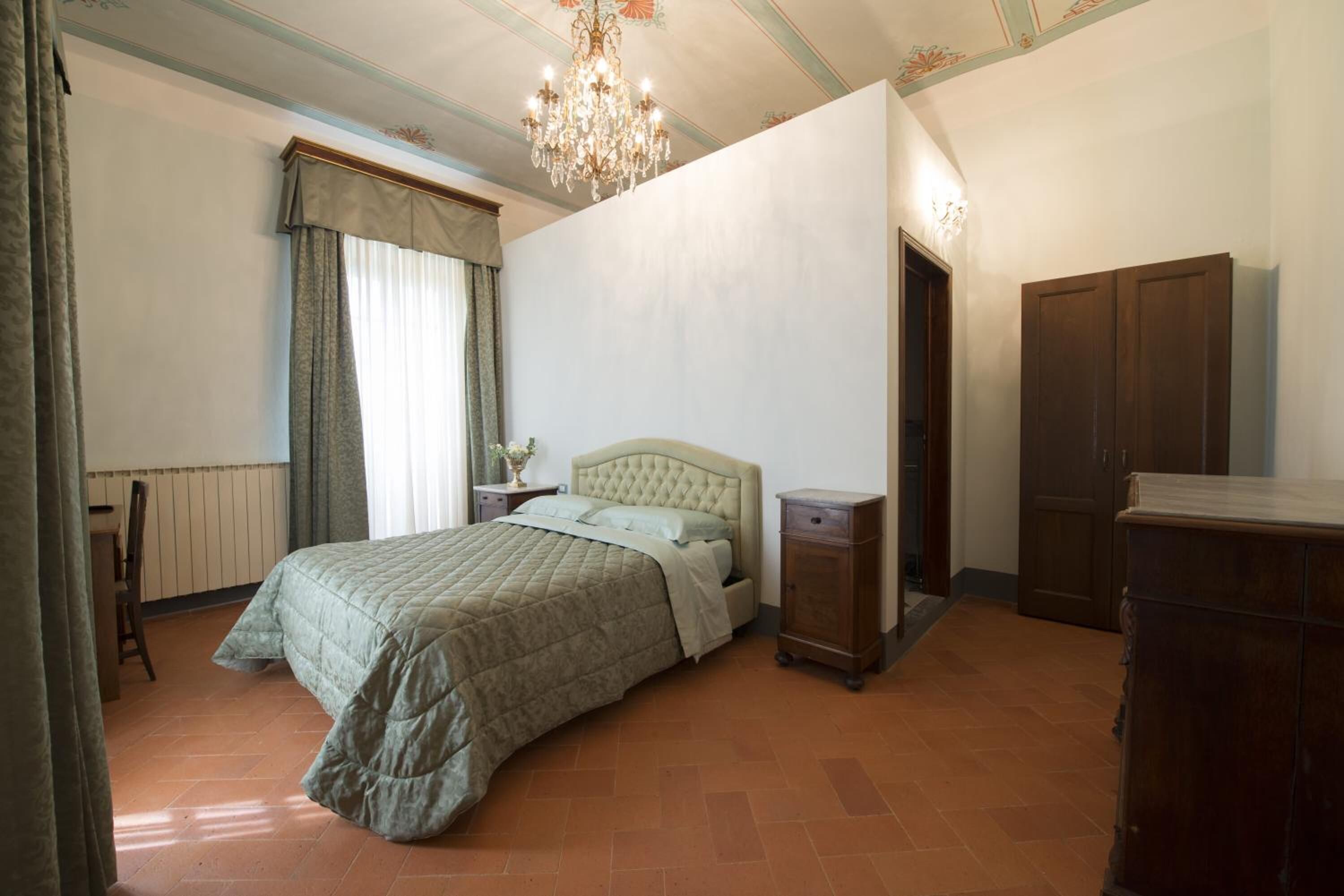 A bedroom with a bed, nightstands, a dresser, and a chandelier.