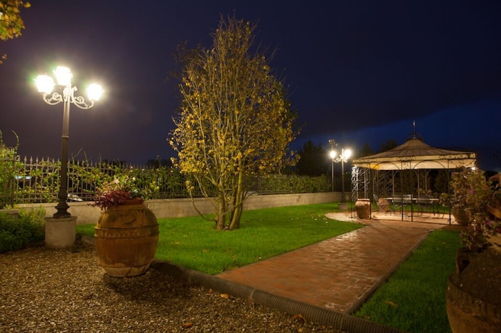 A well-lit garden area with a gazebo, a tree, and a pathway.