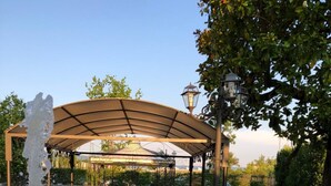 An outdoor dining area with a pergola, tables, chairs, and a fountain. - Relais Villa Scarfantoni B&B (Montemurlo)