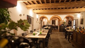A restaurant with a rustic interior, featuring exposed wooden beams, stone walls, and arched doorways. Tables are set with wine glasses and plates, and there is a bar area in the background. - Relais Villa Scarfantoni B&B (Montemurlo)