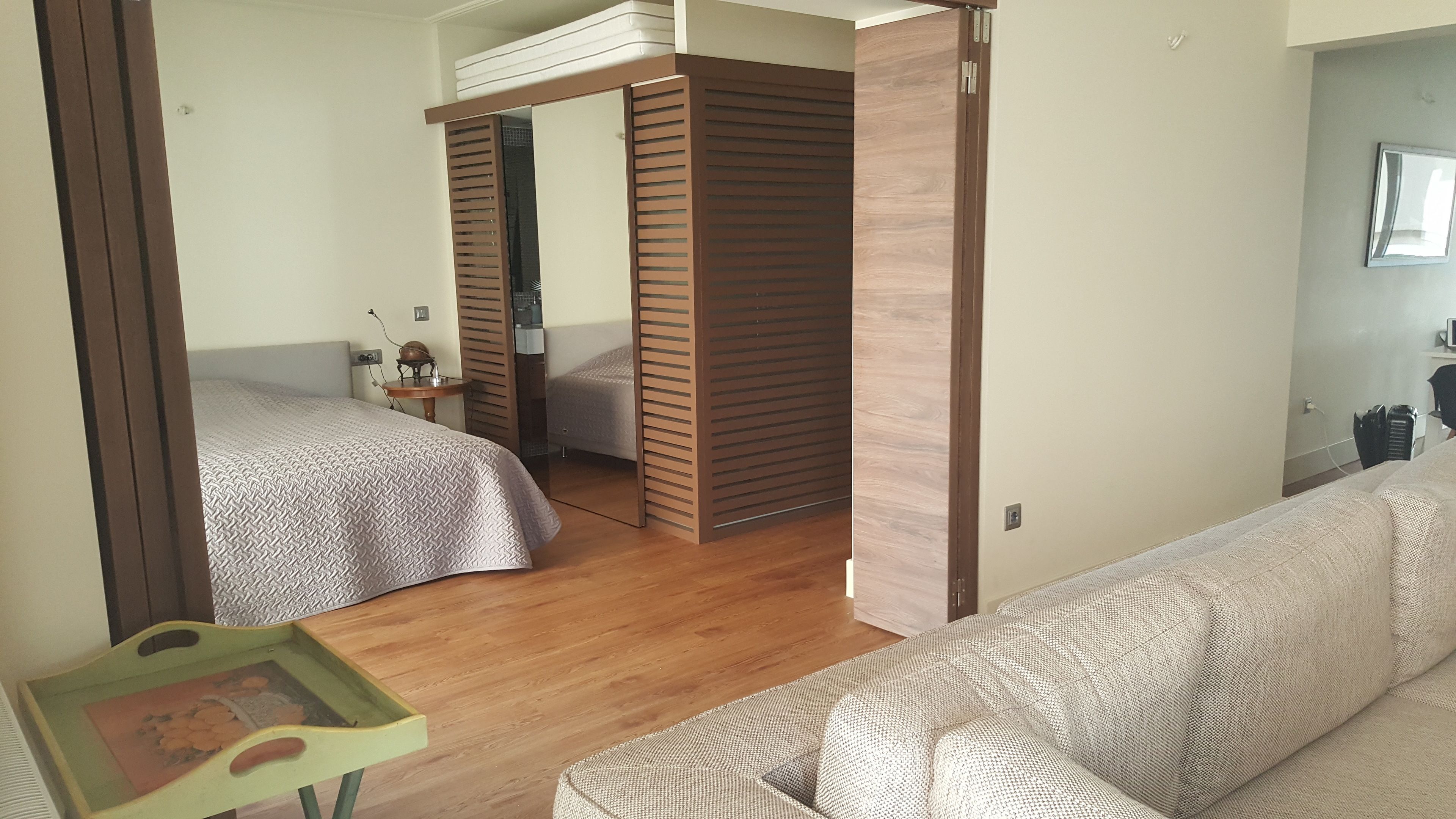 A bedroom with two beds, a wooden wardrobe, a small table, and a sofa.