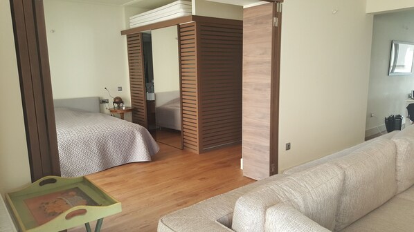 A bedroom with two beds, a wooden wardrobe, a small table, and a sofa. - Captain's Luxury Suite (Nea Smirni)