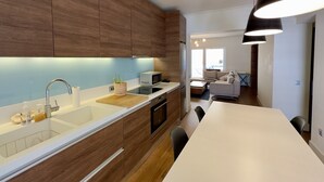 A modern kitchen with wooden cabinets, a white countertop, and a built-in oven. - Captain's Luxury Suite (Nea Smirni)