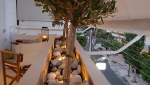 A planter box with a small tree and pebbles, located on a balcony with a view of the street below. - Captain's Luxury Suite (Nea Smirni)