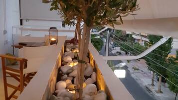 A planter box with a small tree and pebbles, located on a balcony with a view of the street below.