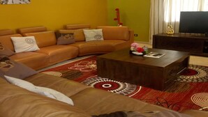 Una sala de estar con un sofá modular, una mesa de centro y un televisor de pantalla plana.