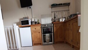 Une cuisine avec des meubles de rangement en bois, un four à micro-ondes, une cuisinière et un réfrigérateur.