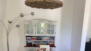 Uma mesa de jantar com jogos americanos trançados, um vaso de rosas vermelhas e um lustre.