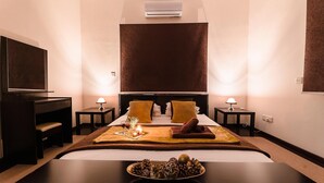 Une chambre d’hôtel avec un grand lit, deux tables de chevet avec des lampes, un téléviseur à écran plat et un plateau décoratif orné de pommes de pin.