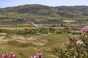 A rural landscape with rolling hills, a winding road, and wind turbines in the distance.