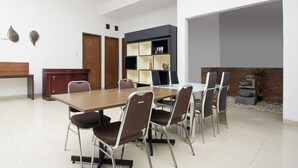 Un espace repas moderne avec une longue table, six chaises, un bureau en bois et une bibliothèque intégrée.
