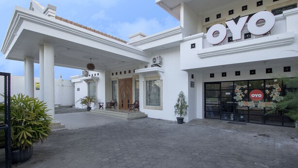 L’entrée d’un hôtel, avec une enseigne « OYO » bien visible, un espace d’entrée abrité et des plantes en pot.