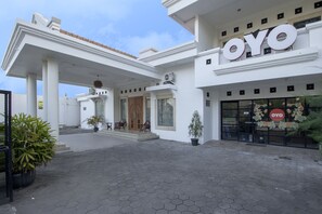 Ein Hotel mit Eingangsbereich, einem gut sichtbaren 'OYO'-Schild, einer überdachten Vorhalle und Blumentöpfen.