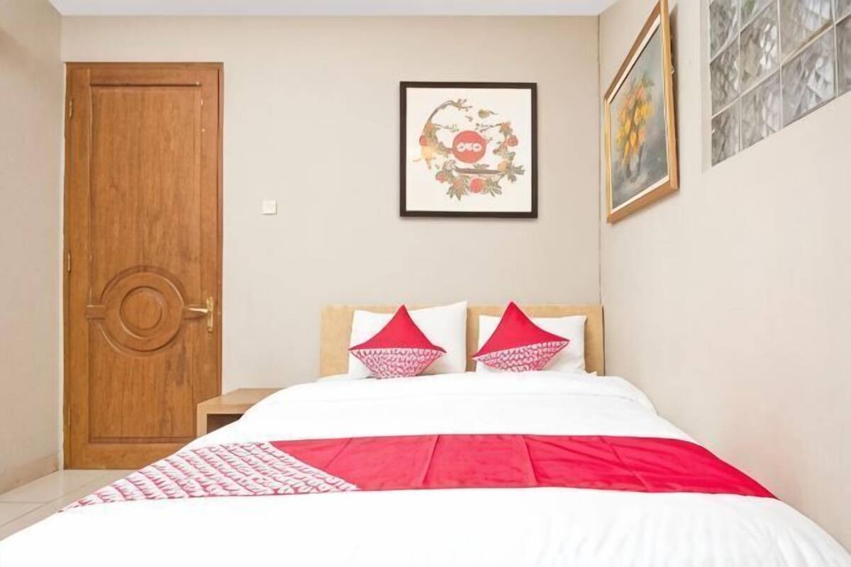 Ein Schlafzimmer mit einem Bett, einer Holztür und einem gerahmten Bild an der Wand.