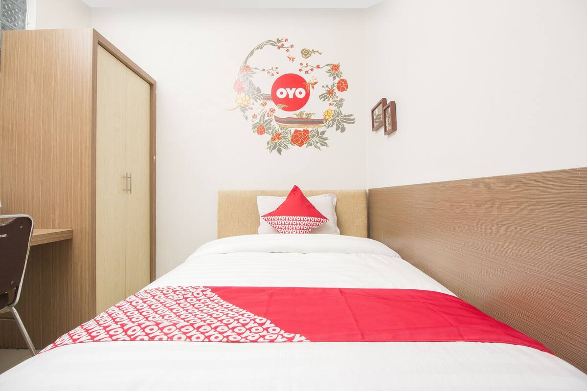 Ein Schlafzimmer mit einem Bett, einem Holzschrank, einem Schreibtisch und einer Wanddekoration.