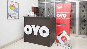 Un comptoir d’accueil avec une grande enseigne « OYO », une carte et une banderole promotionnelle pour les hôtels OYO.