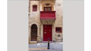 Un edificio con una puerta roja y un balcón.