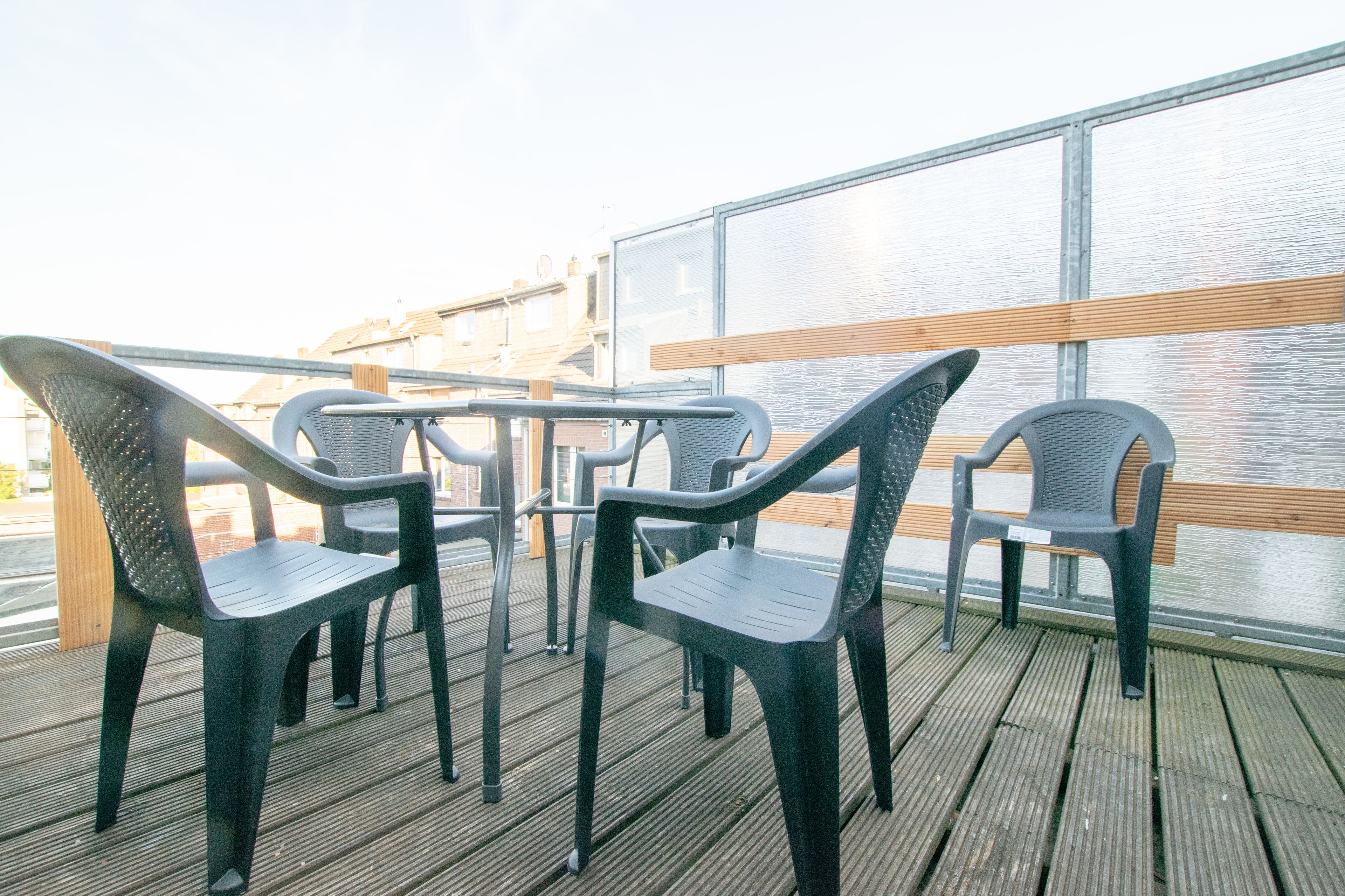 Une terrasse avec des chaises et une table en plastique, donnant sur une étendue d’eau.