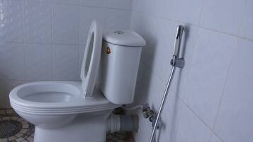 Des toilettes avec un abattant fermé, un bidet fixé au mur et un sol carrelé.